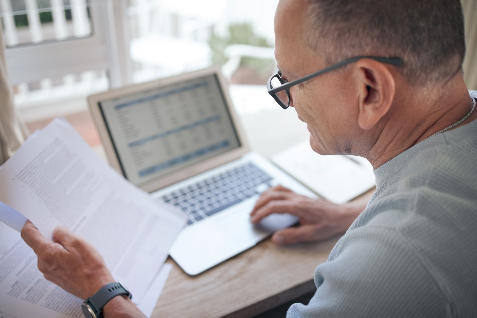 Shot of a mature man reading over financial documents while working